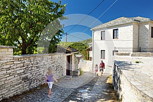 Father and kids exploring Monodendri village with its traditional stone-made buildings and stone walkways, Zagoria area, Epirus,