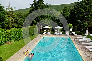 Father and kids having fun in outdoor pool. Children learning to swim. Kids having fun with water toys. Family fun in a pool.