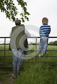 Father With Kids Looking At Lush Landscape By Fence