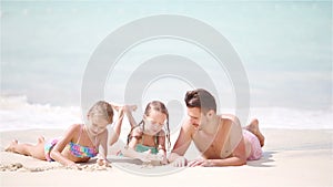 Father and kids lying on white beach