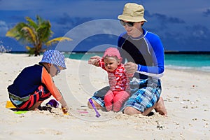 Father and kids making sand castle at tropical beach