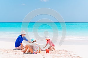 Father and kids making sand castle at tropical beach. Family playing with beach toys