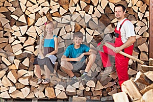 Father and kids prepared to chop firewood and stack it into a wood shed