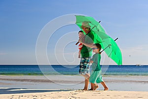 Father and kids with umbrellas on beach vacation