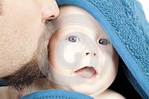 Father kiss 3-month old smiling baby girl hideing in blue blanket