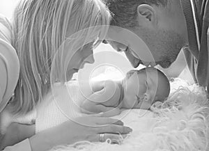 Father kisses a newborn baby. Happy father`s day! Mom, dad and baby. Black and white portrait of a family with a newborn