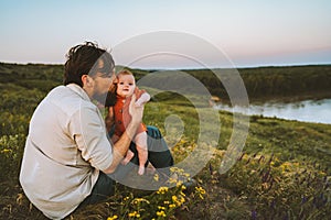 Father kissing baby daughter walking outdoors happy family