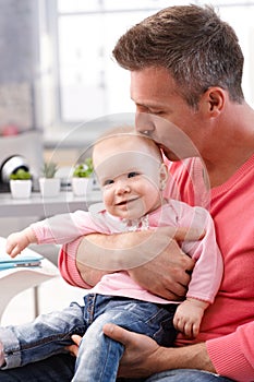 Father kissing happy baby daughter