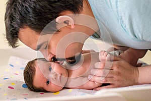 Father kissing little newborn daughter. Baby is looking at camera with surprised face. Fatherhood concept