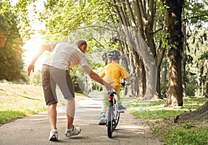 Father learn his little son to ride a bicycle photo