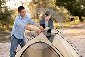 Father learn his son set up camping tent on summer forest glade. Camping people outdoor lifestyle