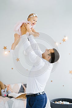 Father lifting baby girl. Happy father picks up and throws his lifting a small child. Home atmosphere, happy family laughing baby