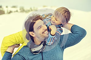 Father lifting his son affectionately in the snow with tenderness