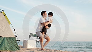 Father lifting son in the air playing together on beach in holiday vacation time at sunset