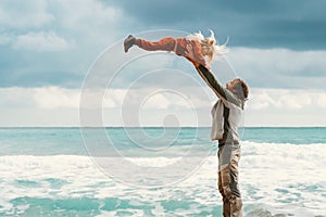 Father lifting up daughter family playing together outdoor dad with child on the beach summer vacations healthy lifestyle