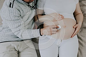 Father listens with stethoscope to baby`s heartbeat.