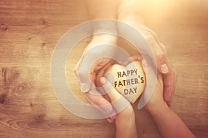 Father and little child holding together wooden heart. Happy father`s day concept