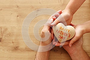 Father and little child holding together wooden heart. Happy father`s day concept