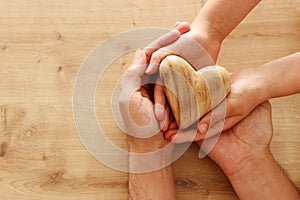 Father and little child holding together wooden heart. Happy father`s day concept