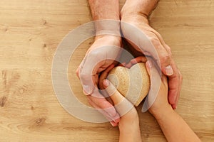 Father and little child holding together wooden heart. Happy father`s day concept