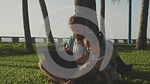 Father with little cute girl using laptop together at park in slow motion.