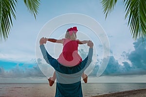 father and little daughter play on beach at sunset