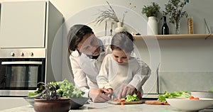 Father and little daughter prepare vegetable salad in the kitchen