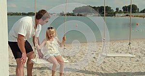 Father and little daughter on a swing at the beach