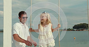 Father and little daughter on a swing at the beach