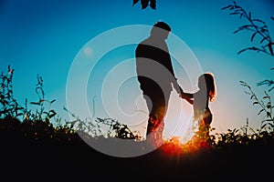 Father with little daughter walk at sunset