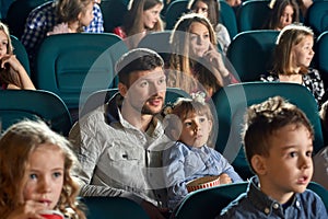 Father with little daughter watching movie in the cinema.