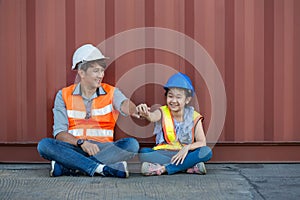 Father and little daughter wearing a safety helmet at Container cargo site. Business heir concept. Happy father and daughter weari