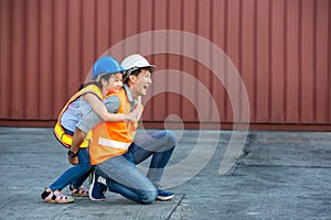 Father and little daughter wearing a safety helmet at Container cargo site. Business heir concept. Happy father and daughter weari