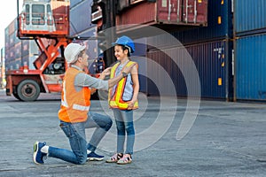 Father and little daughter wearing a safety helmet at Container cargo site. Business heir concept. Happy father and daughter weari