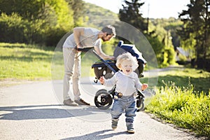 Father with little son and baby daughter in stroller. Sunny park.