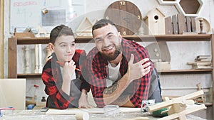 Father and little son giving high five while visiting woodworking masterclass.