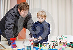 Father and little son having fun on toy exposition, indoors.