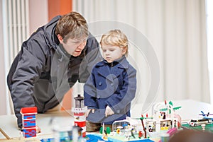 Father and little son having fun on toy exposition, indoors.