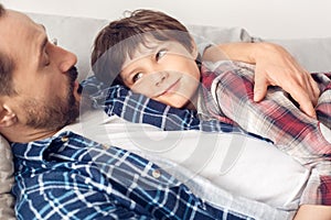 Father and little son at home lying on sofa boy looking at dad relaxed close-up