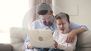 Father and little son laughing on funny videos on internet