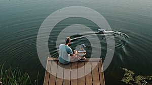 Father and little son play with RC toy speedboat on the lake