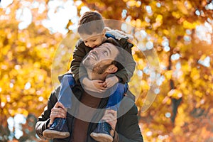 Father and little son playing and having fun outdoors over autumn park background