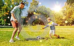 father with little son playing soccer at park