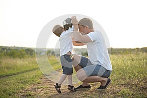 father with a little son plays football on the green grass in the park. Happy family having fun and playing football