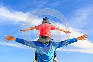 Father and little son on shoulders play at sky