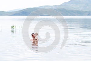 Father with little son swimmind in sea, beautiful landscape sea and mountines