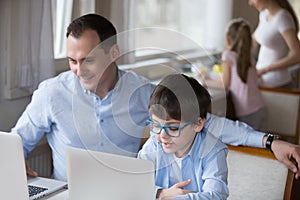 Father and little son using laptop sitting at home