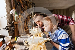 Father and little son with wood plank at workshop