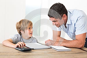 Father looking at son doing homework