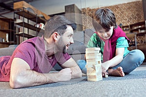 Father looking at son playing jenga game